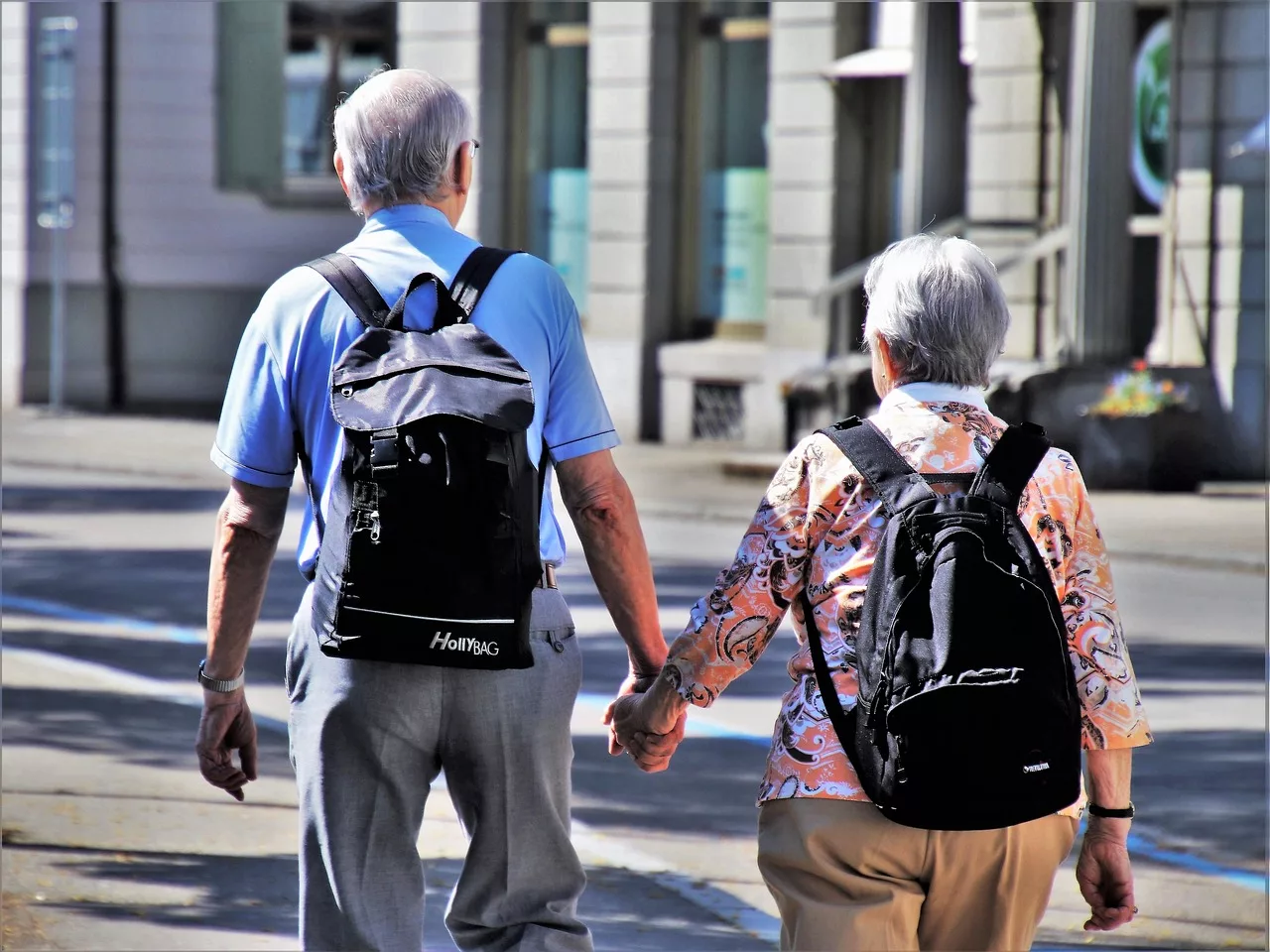 Twee ouderen lopen hand in hand over straat