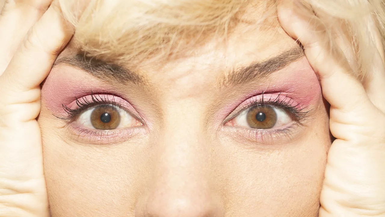 Vrouw trekt de huid rond haar ogen omhoog met haar handen