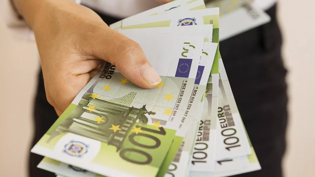Man biedt een stapel van 100 euro biljetten aan